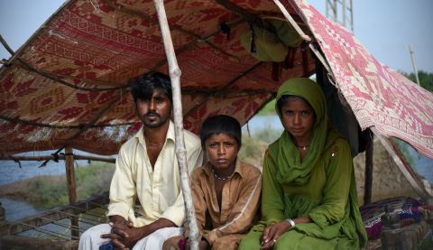 A family sits under temporary shelter after floods in Sindh, Pakistan