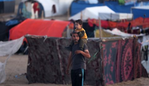 A man carrying his child on his shoulders at a camp in Gaza for displaced Palestinians.