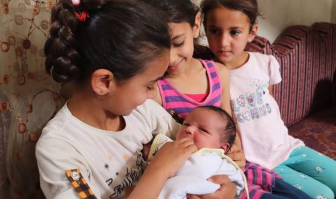 Baraa's daughters lovingly hold their newborn baby sister, Lynn