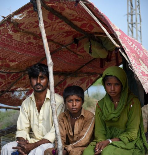 A family sits under temporary shelter after floods in Sindh, Pakistan