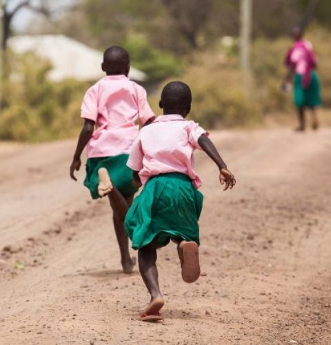 Two girls making their way to school in Kenya. Many girls living in poverty are subject to catcalling and street harassment on their way to and from school