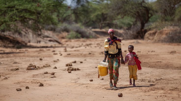 Consolata, with her daughter Elizabeth, 7, carrying jerry cans from the watering hole back to their home in Kenya.